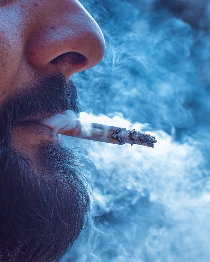gallery-5 Intimate close-up of a bearded man enjoying a cigarette, surrounded by smoke.