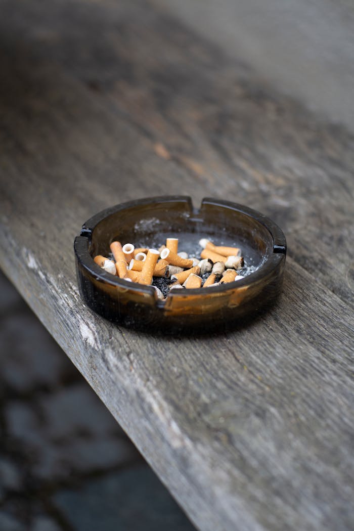 gallery-4 Detailed view of an ashtray filled with cigarette butts on a wooden surface.