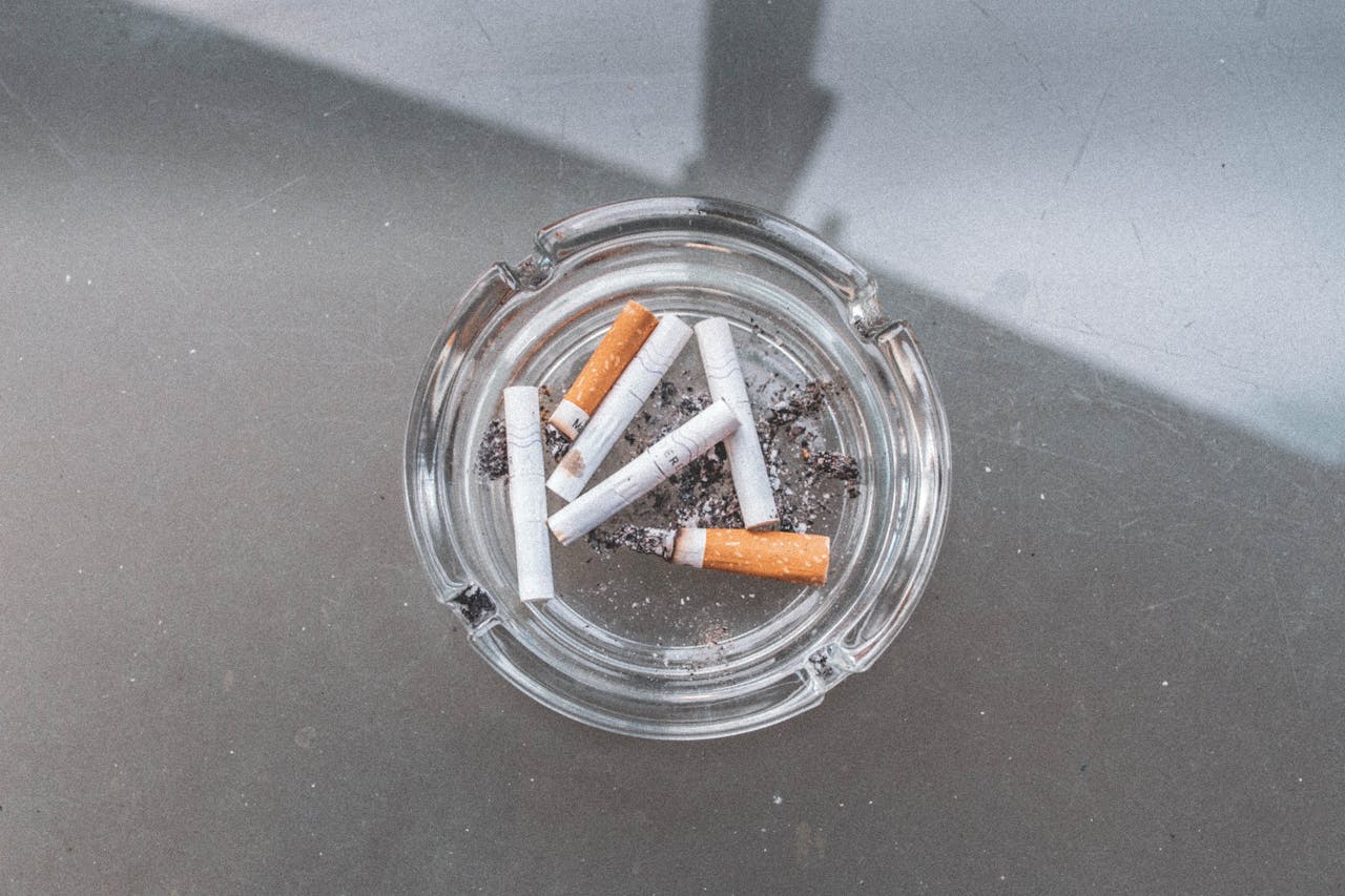gallery-2 Glass ashtray with used cigarettes on a glass table in an outdoor setting.